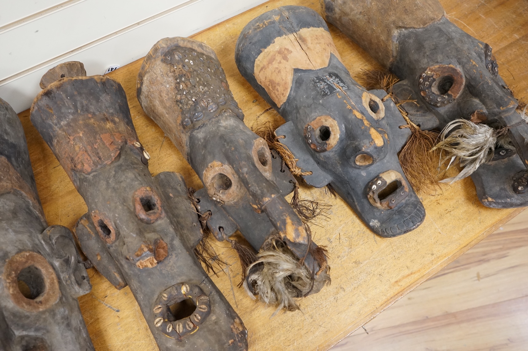 Papua New Guinea Septik River, a collection of five similar carved wooden masks of elongated form, applied in places with shells and two smaller masks with double face carving. Largest 80cm high.